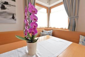 een vaas met paarse bloemen op een tafel bij Villa sulla passeggiata in Ortisei