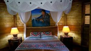 1 dormitorio con 1 cama con una pintura en la pared en Insolite Ara Wakan / Ma cabane, en Pointe-Noire