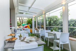 リッチョーネにあるHotel Aldebaranの白いテーブルと椅子、窓のあるレストラン