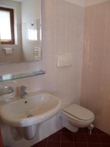 uma casa de banho branca com um lavatório e um WC em Hotel Derby em Aprica