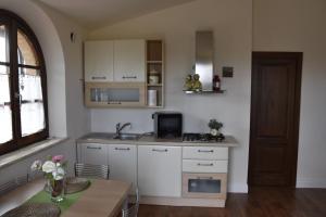 una cucina con armadi bianchi, lavandino e tavolo di La Torre House a San Quirico dʼOrcia