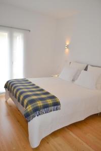 uma cama branca com um cobertor amarelo e azul em TP BOMBARDA 5, Lisbon Deluxe Apartment em Lisboa