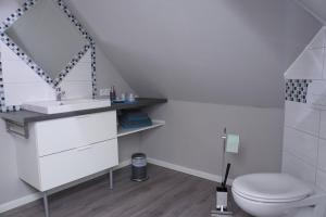 a white bathroom with a sink and a toilet at Ferienwohnung im Schellenpark in Tarp