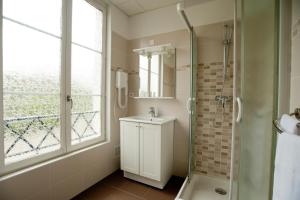 a bathroom with a shower and a sink and a mirror at Logis Hotel Beaudon in Pierrefonds
