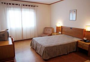 ein Schlafzimmer mit einem großen Bett und einem Stuhl in der Unterkunft Hotel Bom Sucesso in Vila de Prado