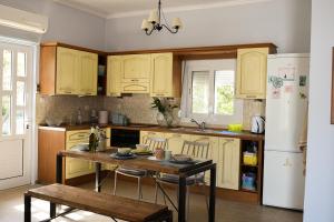 a kitchen with yellow cabinets and a table and a refrigerator at Dimitris' & Valentina's Home in Plakias