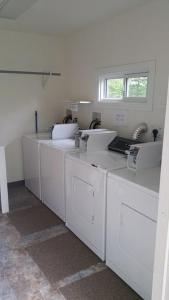 a white laundry room with a row of washing machines at 11 Bridges Campground and Cabin Park in Rosedale