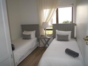 a bedroom with two beds and a table with a window at King Fisher 6 in Mossel Bay