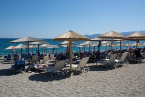 un gruppo di persone seduti su sedie sotto ombrelloni in spiaggia di Land of Gods a Gythio
