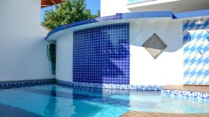 a swimming pool with a blue tile wall next to a house at Recanto das Andorinhas Studios in Paraty