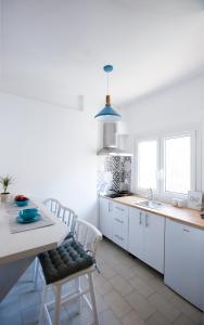 a kitchen with white cabinets and a table and chairs at Kohili apartments in Pefkochori