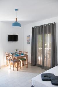a dining room with a table and chairs and a television at Kohili apartments in Pefkochori