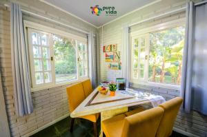 a dining room with a table and chairs and windows at Pura Vida Residence in Morretes +89 photos