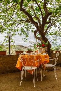 een tafel met een oranje tafelkleed en stoelen onder een boom bij Locanda Etrusca in Bibbona