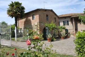 une maison en briques avec une clôture blanche et quelques plantes dans l'établissement Vignano40, à Sienne
