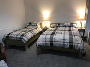 two beds in a room with two lamps on tables at The Pier Hotel in Aberystwyth