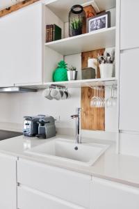 a white kitchen with a sink and shelves at Sloth Loft Montmartre in Paris