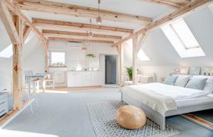 a white bedroom with a bed and a kitchen at Apartamenty Chełmno in Chełmno