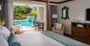 a hotel room with a bedroom with a pool view at Sandals Barbados All Inclusive - Couples Only in Christ Church
