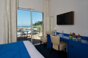 una camera d'albergo con letto e scrivania con TV di Best Western Plus Les Terrasses de Bréhat a Ploubazlanec