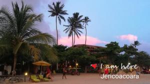 um grupo de pessoas numa praia com palmeiras em Beach house Suites em Jericoacoara