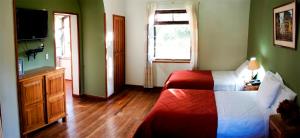 a bedroom with a red and white bed and a television at Centro Vacacional Huaychulo in Concepción