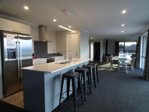 a kitchen with a counter and bar stools in a room at Southholm in Lake Tekapo