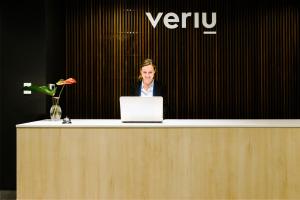 a woman standing behind a counter with a laptop at Veriu Randwick in Sydney