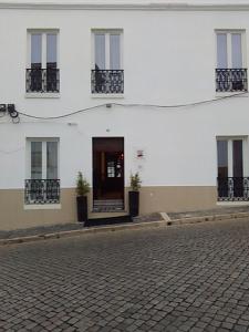 een wit gebouw met een deur in een straat bij Casa Maria Victoria in Beja