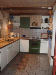 een keuken met een groene kachel en een wastafel bij Country house in Karby