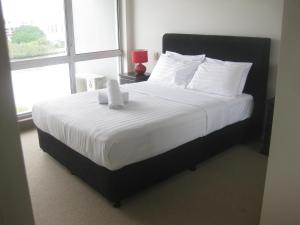 een slaapkamer met een groot bed met witte lakens en een raam bij Fairthorpe Apartments in Brisbane