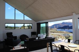 a living room with a table and chairs and windows at Stargate Retreat - Lake Tekapo in Lake Tekapo