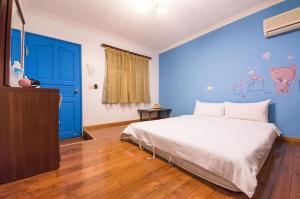台東市的住宿－狗窩民宿，一间卧室设有一张大床和蓝色的墙壁