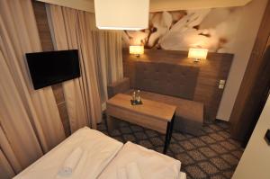 a room with a bed and a table and a television at Pass Hotel in Zebrzydowice