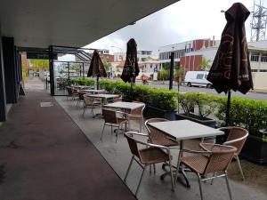 a patio area with tables, chairs and umbrellas at Leichhardt Hotel in Rockhampton