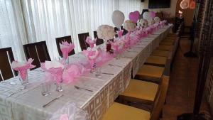 una mesa larga con adornos rosas y blancos. en Hotel Villa Verde en Gŭlŭbovo