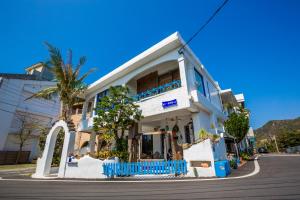 a white building with blue balconies on a street at 墾丁愛情海民宿 in Kenting