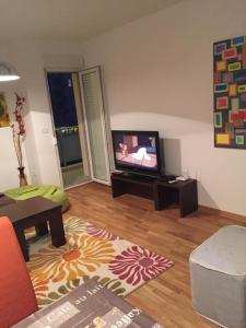 een woonkamer met een flatscreen-tv op een tafel bij Happy Orange in Podgorica