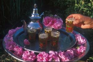 ein Tablett mit vier Getränken, einer Teekanne und Blumen in der Unterkunft Auberge des peupliers Café Restaurant in Akhendachou nʼAït Ouffi