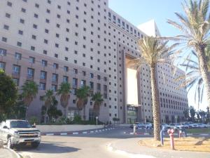 a large building with palm trees in front of it at Haifa Beach Apartment in Haifa