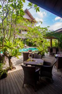 a patio with tables and chairs next to a pool at Puri Sabina Bed & Breakfast in Jimbaran