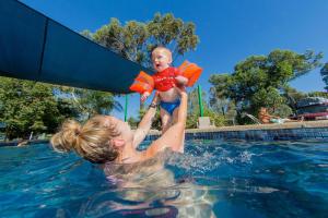 une femme tenant un bébé dans une piscine dans l'établissement Shepparton Holiday Park and Village, à Shepparton