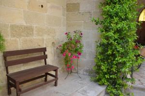 a wooden bench sitting next to a wall with flowers at B&B Lacurte in Martano