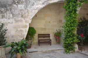 un banco sentado bajo un arco en una pared de piedra en B&B Lacurte, en Martano