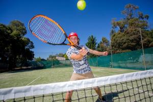 a woman holding a tennis racquet on a tennis court at Shepparton Holiday Park and Village in Shepparton