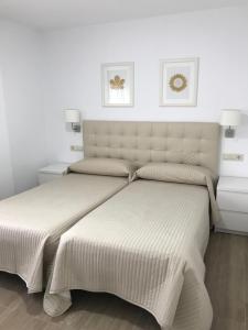 2 camas en un dormitorio con paredes blancas en Viviendas Uso Turístico Arzúa, en Arzúa