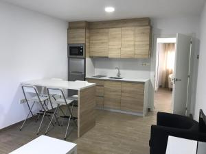 una cocina con encimera y una isla de cocina con taburetes en Viviendas Uso Turístico Arzúa, en Arzúa