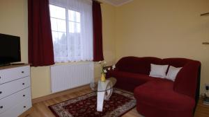 ein Wohnzimmer mit einem roten Sofa und einem TV in der Unterkunft Villa Am Ehrensteig in Eisenach