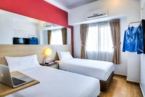 una habitación de hotel con 2 camas y un ordenador portátil en un escritorio en Monoloog Hotel Pasar Baru, en Yakarta