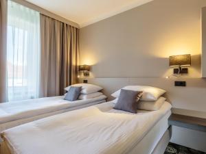 a hotel room with two beds and two lamps at Hotel Center Novo Mesto in Novo Mesto